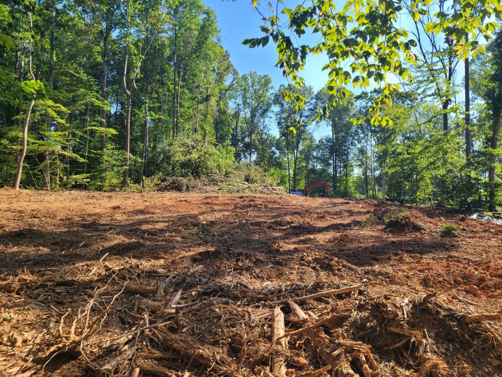 A lot in the process of being cleared with a tackhoe.
