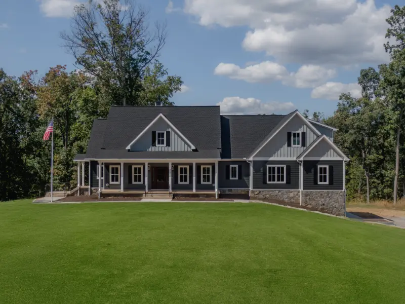 Drone front elevation of a custom home with dark siding and a stone foundation in Warrenton, Virginia