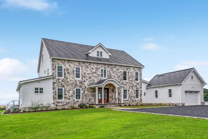 Colonial-style custom ICF estate in Deltaville, Virginia, featuring a full stone facade, arched entry, and attached garage