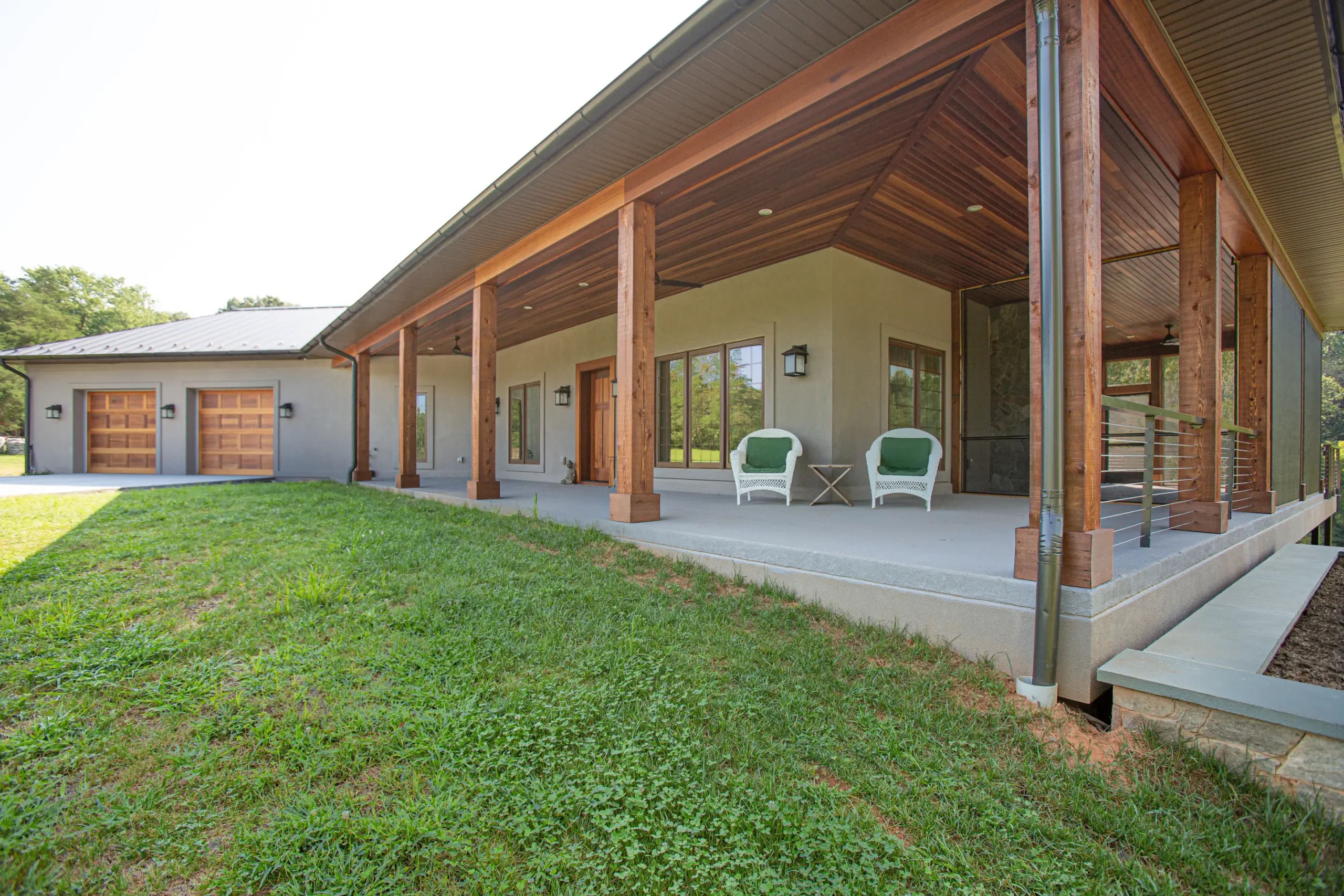 Covered wraparound porch with timber columns and a mahogany ceiling on a modern custom ICF home in Afton, Virginia